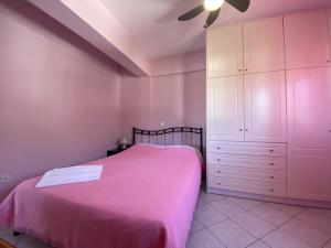 a bedroom with a pink bed and a white cabinet at Soft Horizon Apartment in Loutraki