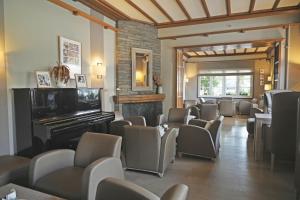a waiting room with chairs and a piano at Hotel des Ardennes in Corbion