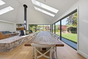 a long wooden table in a room with large windows at Snowline - Ultimate Getaway, Pool, Spa & Tennis in Canobolas