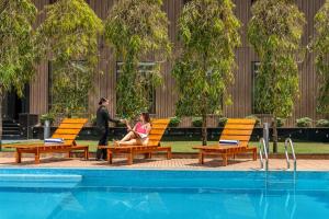 two people sitting on chairs next to a swimming pool at Classic Grande,a Member of Radisson in Imphal