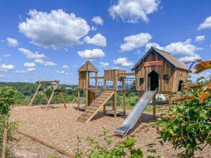 a playground with wooden play equipment and a slide at Hotel des Ardennes in Corbion