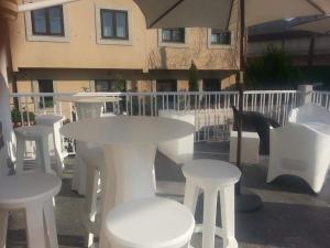 un groupe de tables et de chaises blanches et un parasol dans l'établissement Hostal Restaurante Pasaje, à Candelario