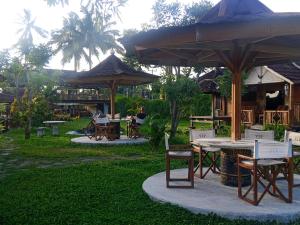 a group of tables and chairs with umbrellas in a park at Naicha Green in Tetebatu