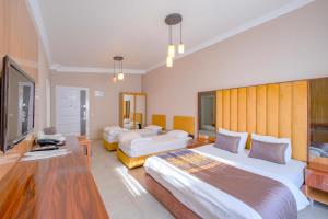 a hotel room with two beds and a television at Arya Apart Kundu Hotel in Lara