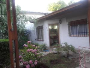 a small white house with a door and some flowers at Las Acacias De Santa Rosa in Santa Rosa