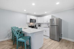 a kitchen with a refrigerator and two blue chairs at Flagler Suites 1 in New Smyrna Beach