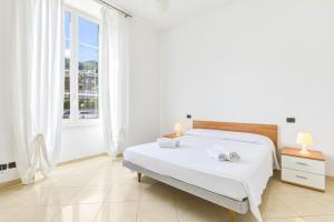 a white bedroom with a bed and a window at Hostdomus - Villa Emma - Zoe e Ascanio in Alassio