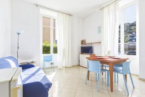 a living room with a table and blue chairs at Hostdomus - Villa Emma - Zoe e Ascanio in Alassio