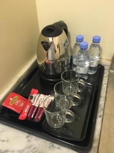 a tray with glasses and bottles of water and a coffee maker at Al Meknan Hotel in Medina