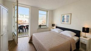a bedroom with a bed and a balcony at CBlue "Apartmenthaus Chrischanshof" in Warnemünde