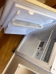 an empty refrigerator with its door open on a wooden floor at Nuit insolite sur un bateau in Cap d'Agde