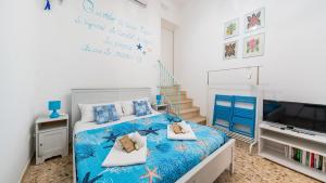 a bedroom with a blue bed with a tv and stairs at La Casa Di Nicole by Rentbeat in Polignano a Mare