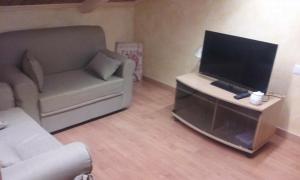 uma sala de estar com um sofá e uma televisão de ecrã plano em B&B Dalle Zie em San Pietro a Maida
