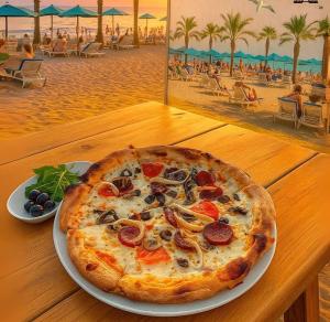 a pizza on a plate on a table next to a beach at Arya Apart Kundu Hotel in Lara +45 photos