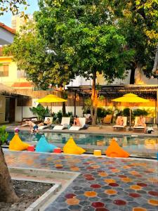 a swimming pool with colorful chairs and umbrellas at THE PLACE Hostel Phnom Penh in Phnom Penh