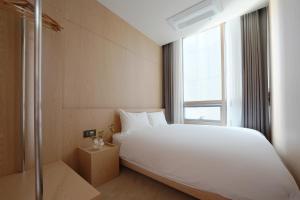 a bedroom with a large white bed and a window at UH Suite The Seolleung in Seoul