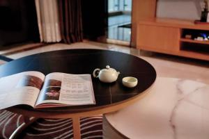 a coffee table with a book and a tea pot on it at Dan Executive Apartment Guangzhou Zhujiang New Town in Guangzhou