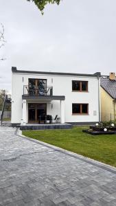 a large white house with a patio in the yard at Lake Apart Residence in Osłonin