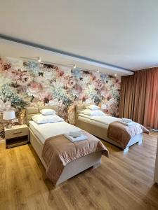 two beds in a room with a floral wall at AMuSE ME in Kielce