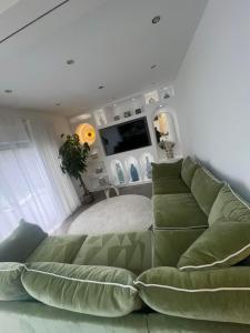 a living room with a green couch and a flat screen tv at 4 Bayswater in New Brighton