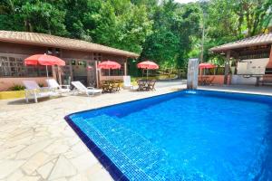 una gran piscina azul junto a una casa en Pérola da Mata, en Boicucanga
