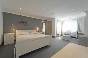 a bedroom with a large white bed and a living room at Hotel des Ardennes in Corbion +21 photos