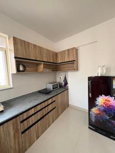 a kitchen with wooden cabinets and a black refrigerator at Live Easy in Siliguri