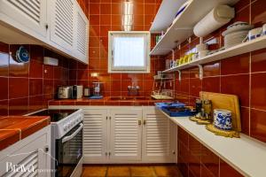 a kitchen with red tiled walls and white cabinets at Can Rino - Vistas panorámicas I piscina I tenis I terraza I Brava Experience in Cadaqués