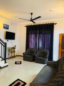 a living room with two chairs and a ceiling fan at Chami Leisure Home in Talpe