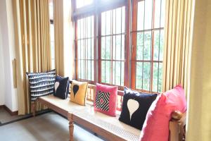 a bench with colorful pillows sitting in front of a window at Muthu Villa, Kandy in Nikawatawana
