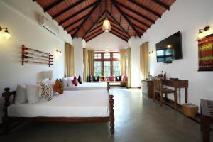 a bedroom with two beds and a desk in a room at Muthu Villa, Kandy in Nikawatawana