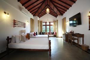 a bedroom with two beds and a desk in a room at Muthu Villa, Kandy in Nikawatawana