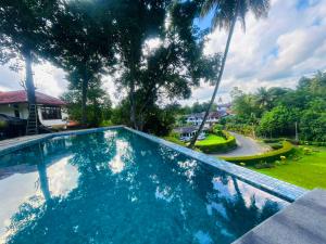 a swimming pool in front of a yard with trees at Muthu Villa, Kandy in Nikawatawana