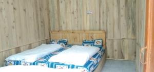 two beds in a room with wooden walls at Hotel Priyanshu in Madheso