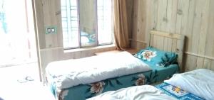 a bedroom with two beds and a window at Hotel Priyanshu in Madheso +4 photos