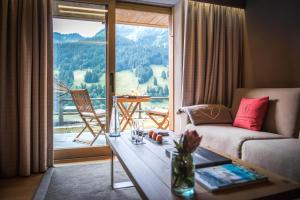 a living room with a couch and a large window at Hôtel de Rougemont & Spa in Gstaad