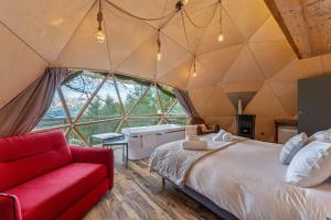 a room with a bed and a red couch at Alpin D'Hôme Hôtel & Spa in Les Orres