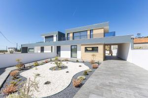 a modern house with a pathway in front of it at Dunes Beach House with Ocean Views in Viana do Castelo