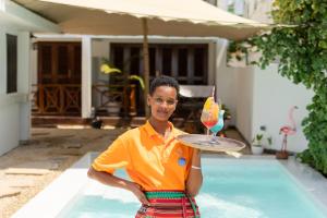 a man holding a tray with a drink on a plate at ZAN Ocean View Hotel in Jambiani +46 photos