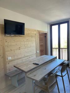 a wooden table with chairs and a television on a wall at Seandre Holiday Apartments in Prada