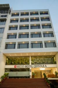 a large white building with stairs in front of it at Mastiff Hotel Crystara, Jalgaon in Jālgaon