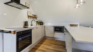 a kitchen with white cabinets and a counter top at Ferny Retreat in Bromyard +16 photos