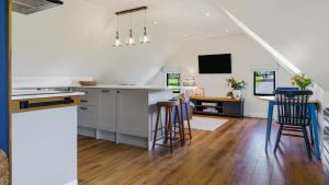 a kitchen with white cabinets and bar stools at Ferny Retreat in Bromyard