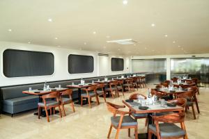 a dining room with tables and chairs and windows at Mastiff Hotel Crystara, Jalgaon in Jālgaon