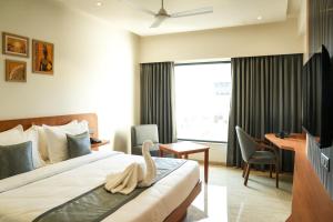 a hotel room with a bed and a desk at Mastiff Hotel Crystara, Jalgaon in Jālgaon +31 photos