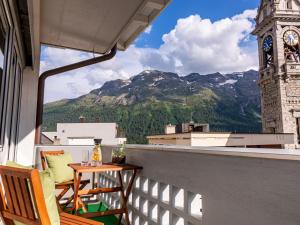 a balcony with a table and chairs and a clock tower at Hotel Arte in St. Moritz