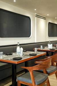 a dining room with tables and chairs and a large window at Mastiff Hotel Crystara, Jalgaon in Jālgaon