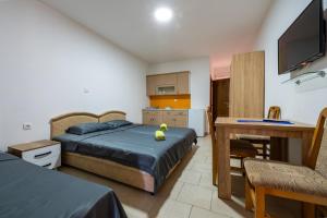 a bedroom with a bed and a desk and a kitchen at Benelux Apartments Bar in Šušanj