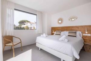 a white bedroom with a large bed and a chair at Naramia Sagaro Villa - with Pool-garden-10 Pax in S'agaro +42 photos