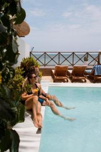 two people sitting on the edge of a swimming pool at ZAN Ocean View Hotel in Jambiani